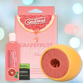 The GoodHead Grapefruit Blowjob Set by Doc Johnson includes a pink bottle of oral gel designed to enhance oral pleasure, a fruit-slice-shaped toy made from ULTRASKYN material, and several additional small packets. The packaging is adorned with a grapefruit graphic and features pink and white text set against a pastel background.